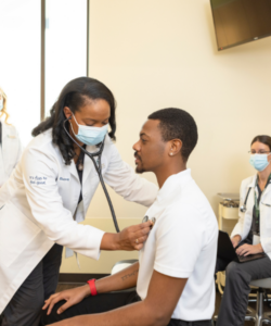 Clinician performing a physical examination on a patient, demonstrating thorough and professional care in a clinical setting.